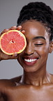 Grapefruit, happy beauty and face of woman in studio for vitamin c cosmetics, collagen or glow on grey background. African model, citrus fruits or laugh for eco skincare, sustainable benefits or diet