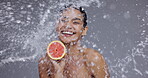 Smile, water splash and grapefruit for beauty with woman in studio on gray background for hygiene or hydration. Portrait, skincare and happy young person with food for health, diet or nutrition