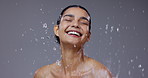 Water splash, beauty and face of woman on gray background for cleaning, wellness and cosmetics. Dermatology, skincare and person with drops for washing, facial treatment and healthy skin in studio