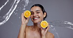 Face, water and woman with skincare, fruits and smile with cosmetics, aesthetic and grooming on grey studio background. Portrait, person or model with h20, splash or orange with nutrition or wellness