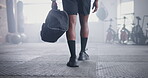 Person, athlete and walking with bag in gym for boxing challenge for competition, physical activity or wellness. Legs, shoes and muscle in training for fight workout or exercise, confident or health