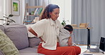 Mother, baby and backache on sofa in pain, discomfort or inflammation with sore joint or spine at home. Mom with injury or holding little child, kid or newborn toddler with bad posture in living room