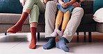 Feet of mom, dad and kid on sofa with socks, love and bonding together in living room of home. Legs of family with father, mother and daughter sitting on couch, relax and care in lounge of apartment.