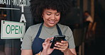 Black woman, phone and open cafe by door for communication, social media or networking. Happy African female person or waitress smile on mobile smartphone in online chatting or texting at coffee shop