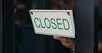 Closed, sign and person in window of small business, coffee shop or end of service at restaurant. Store, notice and closeup on hands of owner to change signage, board and information of closing time