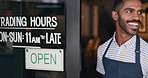 Open, sign and happy man at window of small business, coffee shop or start of service at restaurant. Store, notice and hands of owner change signage, board or information of operating time in morning