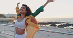 Woman, dance and celebration by beach outdoor with happiness, travel adventure and relax in summer. Young person, positive and dancer with freedom, energy and creative movement on sidewalk by ocean