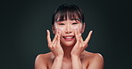 Skincare, cream and face of happy woman in studio with collagen product, moisturizer and beauty routine. Dermatology, cosmetics and Asian girl with lotion for anti aging benefits on green background.