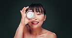 Woman, Asian and cream for beauty, face and skincare with moisturizer, dermatology and wellness on grey background. Antiaging, lotion container and eye with product, cosmetic care for skin in studio