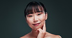 Korean, beauty and woman with skincare on face in studio with confidence and pride from dermatology. Happy, girl and smile for healthy glow on natural skin from facial or cosmetics in dark background