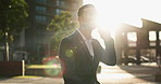 Businessman, phone call and talking outdoor in city with walking, networking and communication. Entrepreneur, employee and person with smartphone for chat, discussion and consulting with lens flare