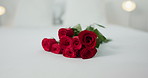Romance, flowers and roses in bedroom for love on valentines day, anniversary celebration and honeymoon. Red rose, bouquet and closeup of florals on bed for romantic date, occasion and luxury in home