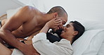 Happy couple, relax and kissing on bed for morning, romance or love in embrace, trust or care at home. Young man and woman smile lying in bedroom for intimacy, passion or bonding together at house