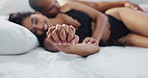 Happy couple, relax and holding hands on bed for love, morning or romance in embrace, trust or care at home. Young man and woman smile lying in bedroom for intimacy, passion or bonding at house