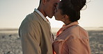 Couple, love and kiss on beach for happy date, romance and celebration of valentines day in sunset or lens flare. Excited woman and man together by ocean for anniversary, holiday and relationship 