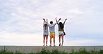 A group of excited friends celebrating with their arms in the air together