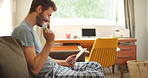 A young man making a card payment using his digital tablet in his lounge