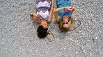 Two friends lying on a gravel dirt road together while one woman checks her watch