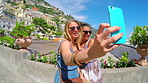 Two women taking selfies together using a smartphone while on holiday