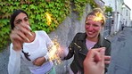Two happy friends cheerfully using sparklers while on holiday together