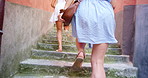 Two excited friends running up stairs together while on holiday