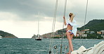 Young woman in bikini on a yacht enjoying the view of an Italian village in the distance. Woman in a bikini sailing on a yacht in Liguria, Italy enjoying the view