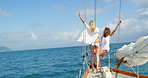 Excited young friends celebrating sitting on a boat during an ocean cruise in Italy. Two cheerful women on holiday together celebrating on a boat cruising around on the Italian ocean