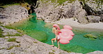 Young woman carrying flamingo inflatable around a lake to swim. Carefree young woman carrying pink flamingo inflatable walking to lake.