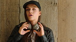 A cool university student with attitude listening to music on her headphones against a wood wall. A cool young woman enjoying her music by listening through her headphones