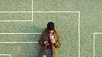 A woman relaxing against a tile wall using her smartphone to send text messages and drinking a cup of iced tea. A young woman using her cellphone to scroll through apps while drinking iced coffee