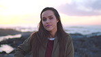 A young woman enjoying the sunrise on the promenade with her hair blowing in her face on a cold, windy day. A young woman on the promenade at sunset on a cold day removing her hair from her face