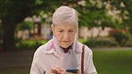Senior woman with phone thinking and reading internet retirement news or online shopping on e commerce store or shop. Elderly person play smart and idea game on cellphone or mobile smartphone at park
