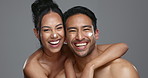 Couple, smile and love for skincare, care and portrait with moisturizer in studio by gray background. Happy people, dermatology and hug for cosmetics, hydration and creme or love for skin treatment