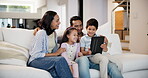 Family, tablet and playing a game on sofa of living room in home together for weekend bonding. Technology, pointing or showing with mother, father and happy children watching video in apartment