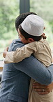 Love, Muslim father and son hug in a house for a hello, reunion or welcome home gesture. Happy family, embrace or Islamic dad greeting an excited boy, kid or child with care, support or bonding 