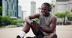 Fitness, phone and happy black man on headphones outdoor, typing in city or streaming audio. Smartphone, sports or person listening to music on mobile app, reading funny meme or laugh on social media