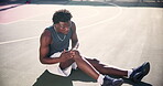 Basketball, knee and black man with injury on a court during a match with a competitive sport game. Leg, pain and accident during active exercise or cardio playing outside with muscle inflammation