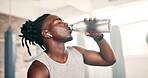 Black man, drinking water and fitness in gym for exercise break and health, boxing energy or training challenge. Thirsty sports person or boxer listening to music and bottle for nutrition in workout 