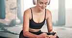 Happy woman, headphones and phone in relax at gym for music, podcast or social media. Female person or athlete on break, rest or listening to sound on mobile smartphone in fitness at health club