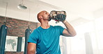 Man, fitness and drinking water on break at gym for hydration, recovery or natural sustainability in workout. Thirsty or tired male person in rest, exercise or breathing with mineral liquid or bottle