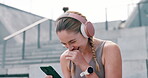 Female athlete, headphones and cellphone to take break, laugh and social media while outside. Woman, sportsperson or student with smart phone, smile and joke at stadium on sunny day in New Zealand