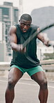 Man, battle ropes and exercise in city for fitness with music, earphones and energy for bodybuilding. Athlete, black person and workout in street or road with power, action and radio for training