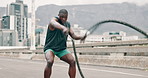 Man, battle ropes and fitness in city for speed workout or health performance for muscle, sport or exercise. Black person, equipment and fast training or urban road for hard work, progress or strong