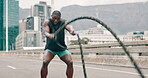 Man, battle ropes and exercise in city for speed workout or health performance for muscle, sport or outdoor. Black person, equipment and fast training or urban road for hard work, progress or strong