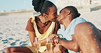 Picnic, alcohol and black couple on beach kiss with champagne toast for anniversary, romance or date. Nature, love and people with drink, embrace or cheers on holiday, vacation and celebration by sea