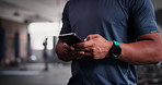 Phone, fitness and hands typing in gym for networking on social media, mobile app or internet. Technology, sports and closeup of man personal trainer or coach on cellphone for online email in studio.