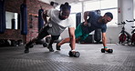 Man, personal trainer and push ups with dumbbells in fitness for workout, exercise or training on floor at gym. Active male person, coach and lifting weights for muscle gain, strength at health club