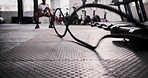 Man, floor and battle rope at gym for fitness, workout or intense training in health and wellness. Active male person, bodybuilder or athlete in arm exercise, cardio or stamina for muscle endurance
