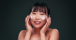 Beauty, cream and face of Asian woman in studio with retinol product, vitamin A and skincare routine. Smile, cosmetic benefits and girl with collagen facial lotion for dermatology on green background