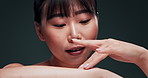 Beauty, skincare and face of Asian woman in studio for body care, treatment or results on black background. Wellness, glowing skin or portrait of Japanese model touching arm for cosmetic satisfaction